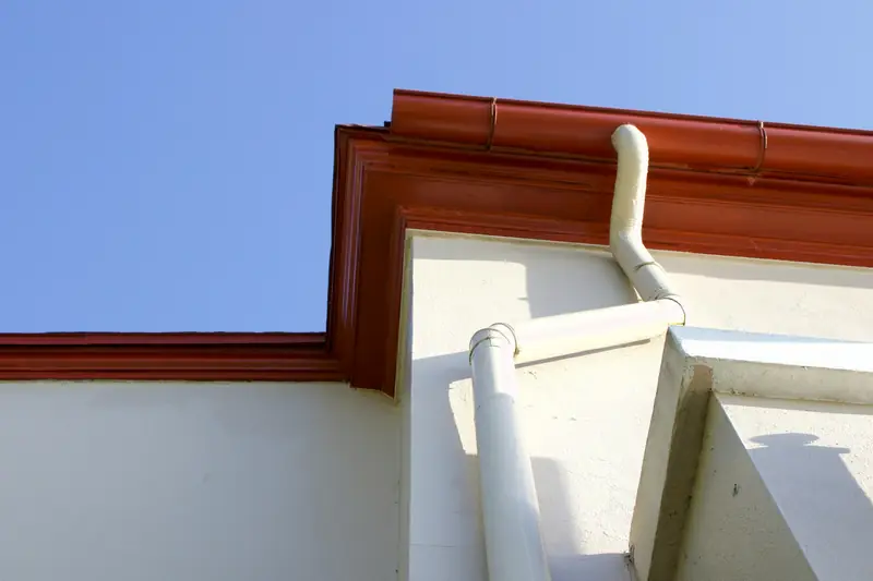 Red spouting and a white downpipe at the corner of a house